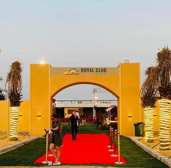 Royal Club Tourism desert camp entrance with red carpet and palm trees