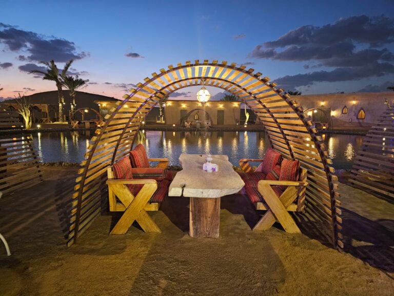 VIP seating under a lit arch by the water at dusk