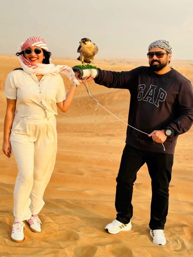 Couple holding a falcon on the dunes during a private safari
