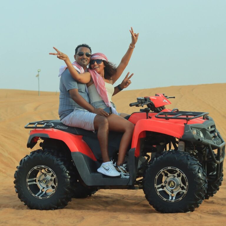 Couple cheering on a red quad bike on the dunes