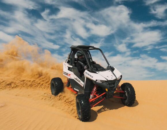 Single-seat Polaris RS1 buggy kicking up sand on the dunes