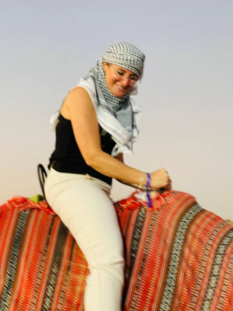 Smiling guest on a camel ride in the golden evening light