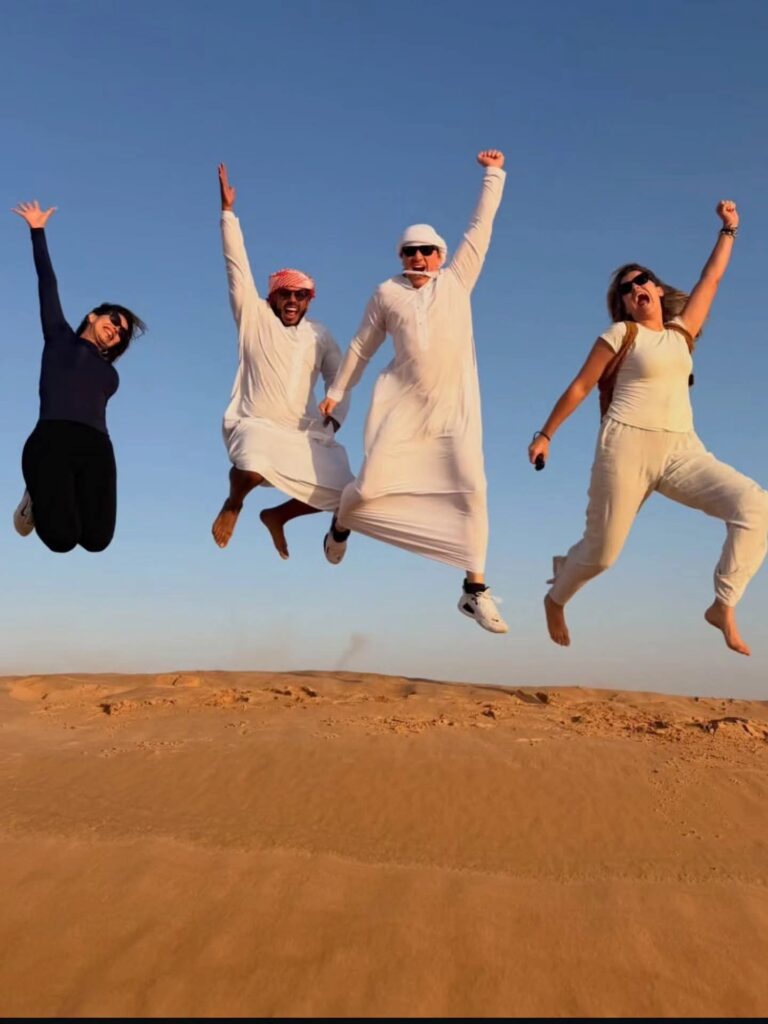 Group of guests jumping on the dunes under a blue sky