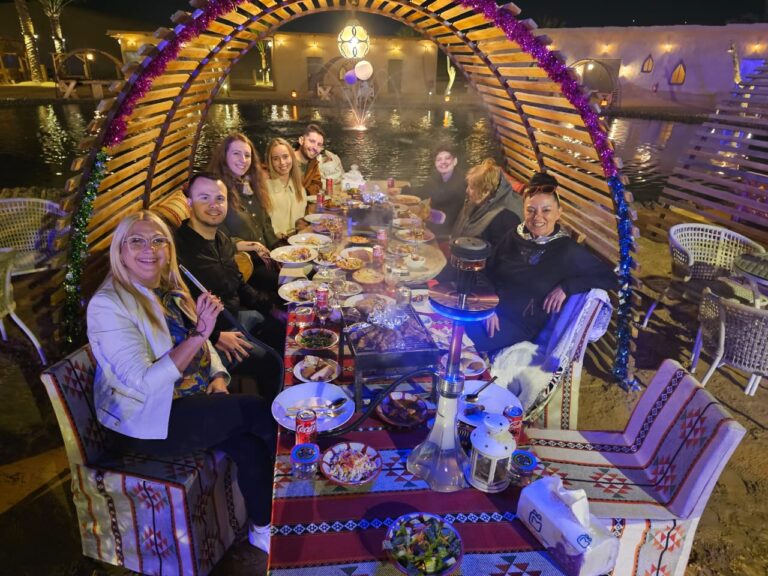 Guests at a VIP dinner table under a lit arch at the desert camp